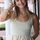Woman wearing a beige peplum top and blue jeans outdoors.