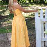 Woman in a strapless dress standing outdoors near a white picket fence.