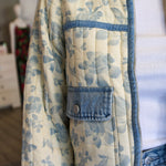 Person wearing a floral quilted jacket with denim accents