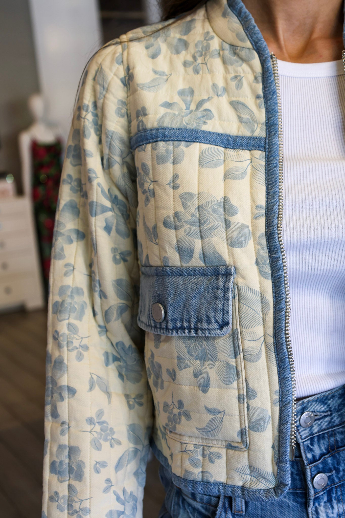Person wearing a floral quilted jacket with denim accents