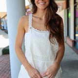 Woman wearing a white lace romper standing outdoors.