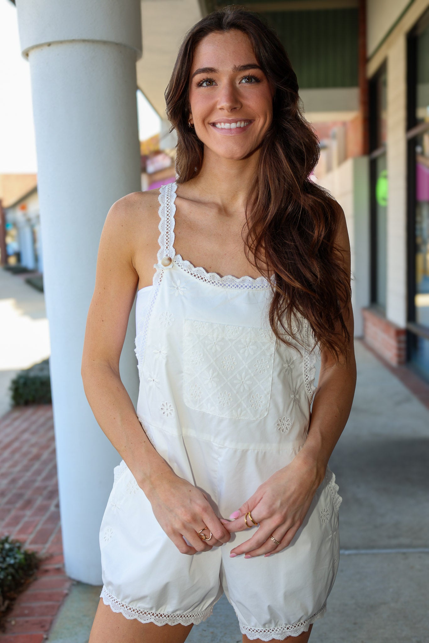 Woman wearing a white lace romper standing outdoors.