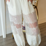 White lace-trimmed pants worn by a person indoors.