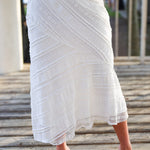 White lace skirt worn by a person on a wooden deck