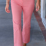 A person wearing red and white gingham cropped pants and a matching red and white gingham top, walking outdoors on a sidewalk.