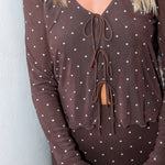 A smiling blonde woman wearing the Amara brown long-sleeve V-neck top with white polka dots by Z Supply and a tie-front detail, paired with a matching brown Eda polka-dot skirt at Rodeo Boutique.