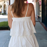 Woman wearing a white eyelet matching set standing outdoors on a sidewalk.