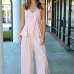 Woman wearing a light pink outfit standing on a sidewalk.