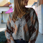 Woman wearing a argyle patterned cardigan standing outdoors.