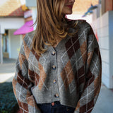 Woman wearing a argyle patterned cardigan standing outdoors.