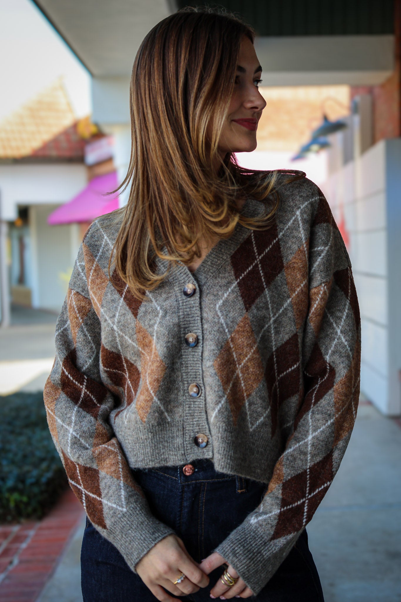 Woman wearing a argyle patterned cardigan standing outdoors.