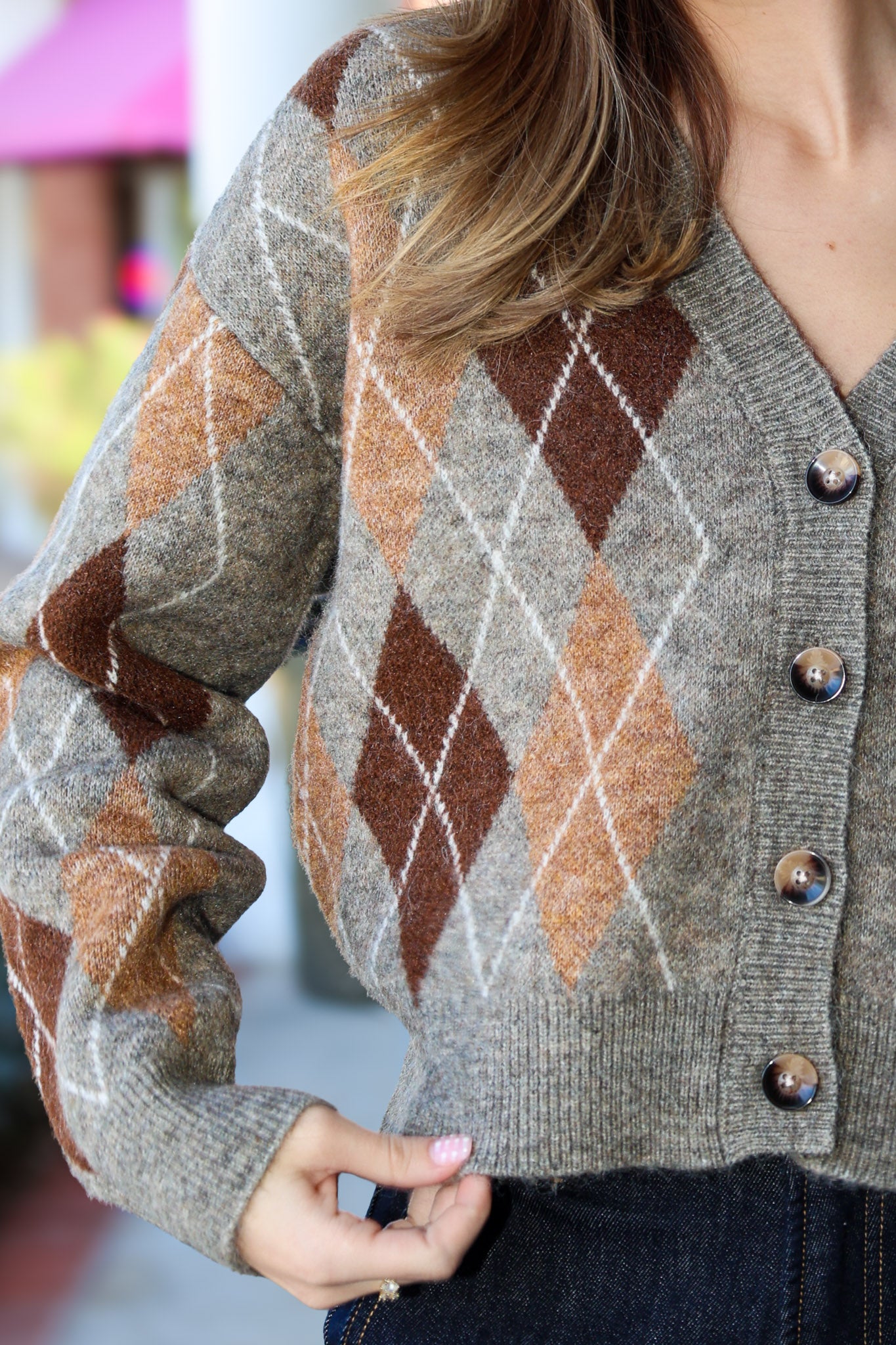 Close-up of a person wearing a argyle patterned cardigan with blurred background