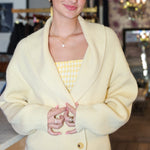Woman wearing a light yellow cardigan over a yellow top in an indoor setting.