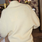 Person wearing a light-colored sweater in an indoor setting