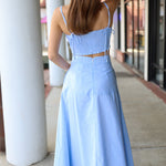 Woman wearing a light blue matching set standing on a sidewalk.