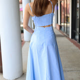 Woman wearing a light blue matching set standing on a sidewalk.