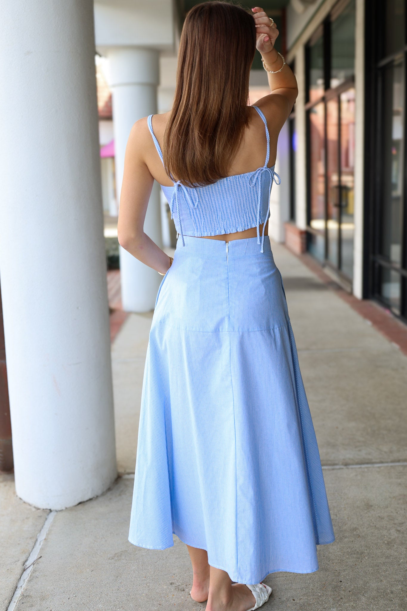 Woman wearing a light blue matching set standing on a sidewalk.