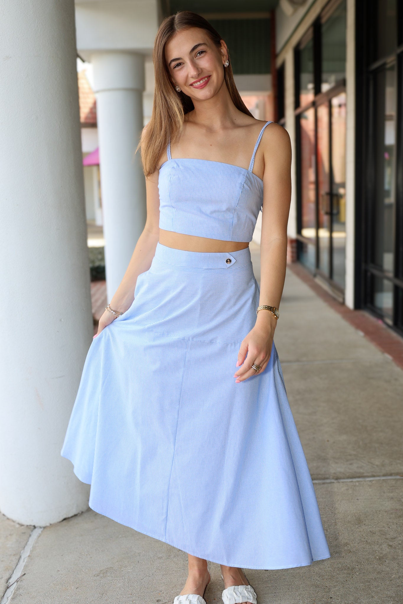 Woman wearing a light blue stripe two-piece outfit standing outdoors.