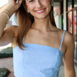 Woman wearing a light blue top with thin straps outdoors