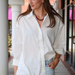 Bea Shirt, NIA - white button down shirt and light blue PISTOLA jeans standing on a sidewalk.