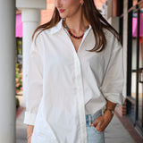 Bea Shirt, NIA - white button down shirt and light blue PISTOLA jeans standing on a sidewalk.