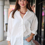 Bea Shirt, NIA - white button down shirt and light blue PISTOLA jeans standing on a sidewalk.