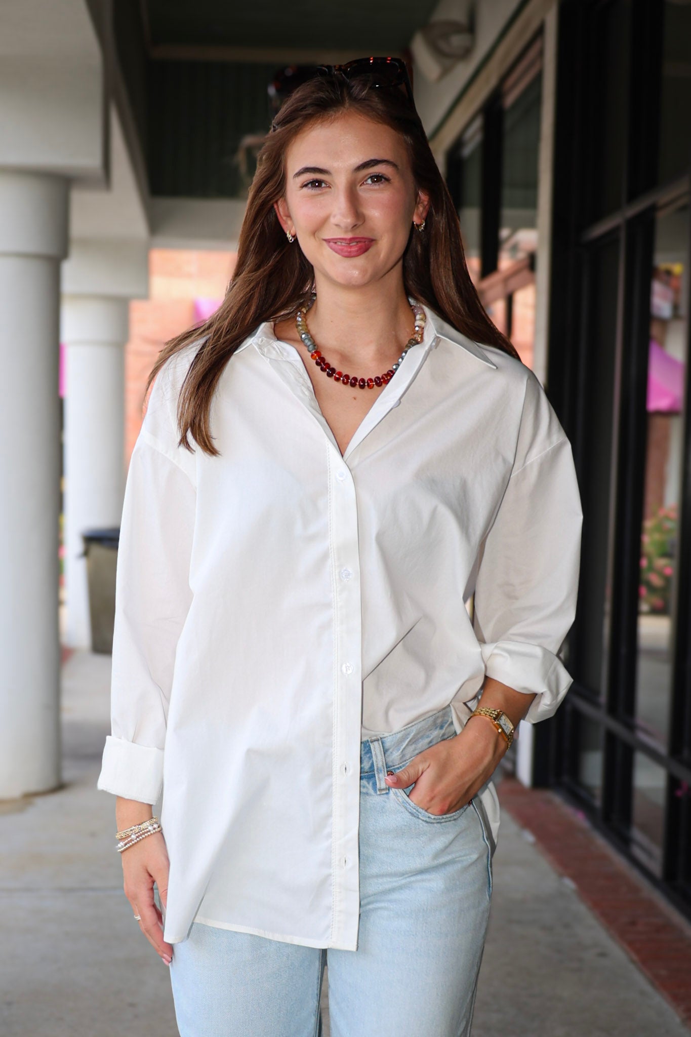 Bea Shirt, NIA - white button down shirt and light blue PISTOLA jeans standing on a sidewalk.