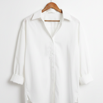 White shirt on a wooden hanger against a white background