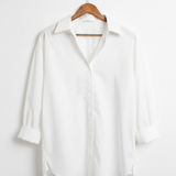 White shirt on a wooden hanger against a white background