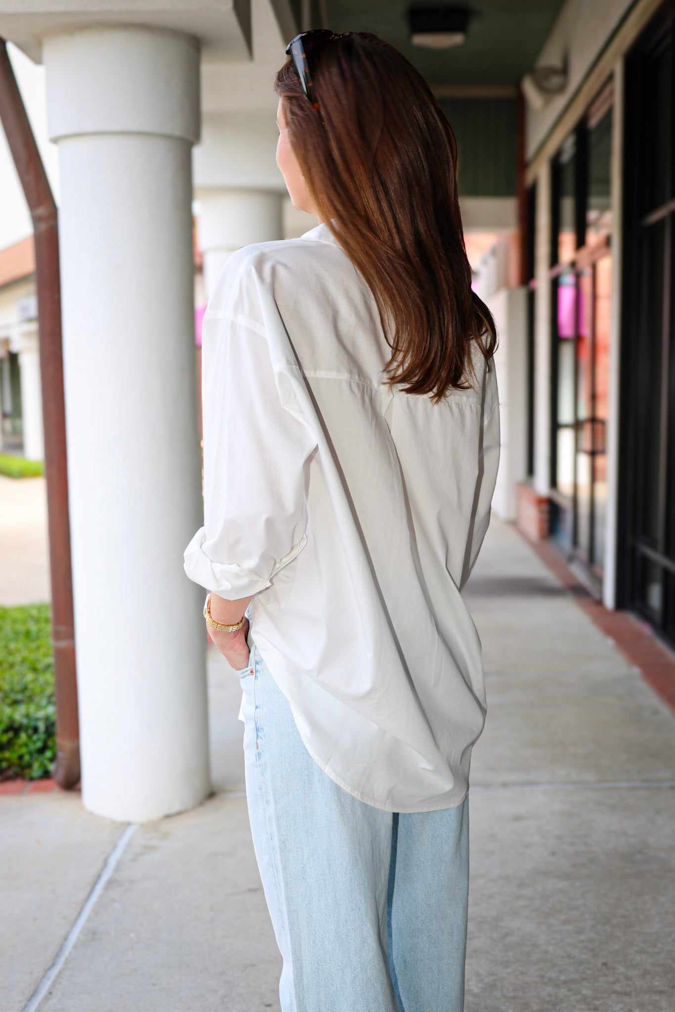 Bea Shirt, NIA - white button down shirt and light blue PISTOLA jeans standing on a sidewalk.
