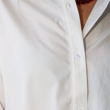 Bea Shirt, NIA - white button down shirt and light blue PISTOLA jeans standing on a sidewalk.