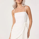 Woman wearing a white dress with a floral detail on a plain background
