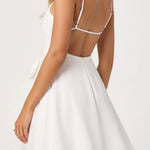 Woman wearing a white dress with thin straps on a plain background