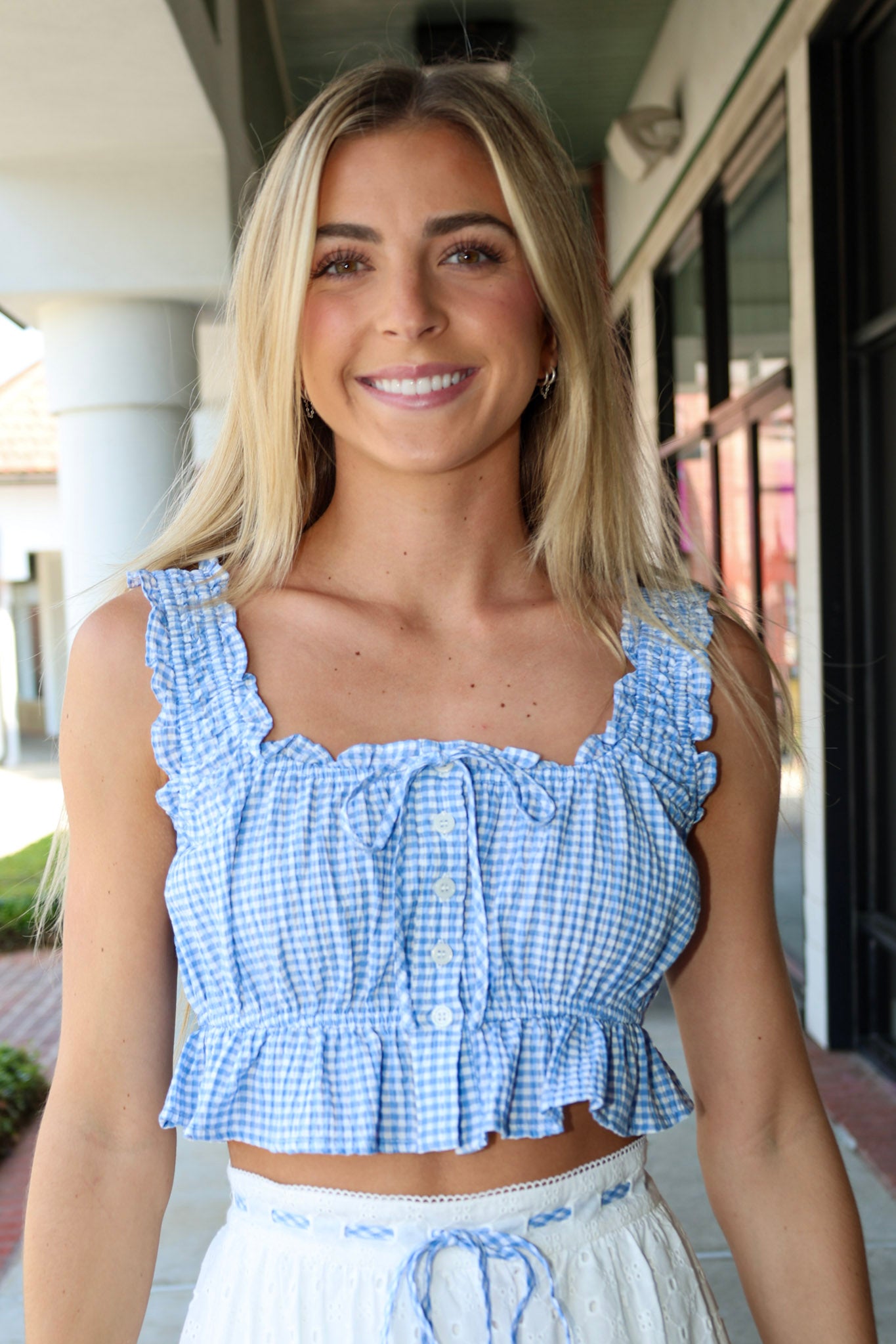 Woman wearing a blue checkered top with ruffled details outdoors.