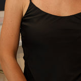 A woman wearing a black-colored satin camisole top and light-wash denim jeans at Rodeo Boutique.
