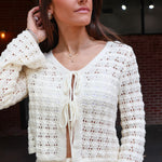 Woman wearing a white crochet outfit with a blurred background
