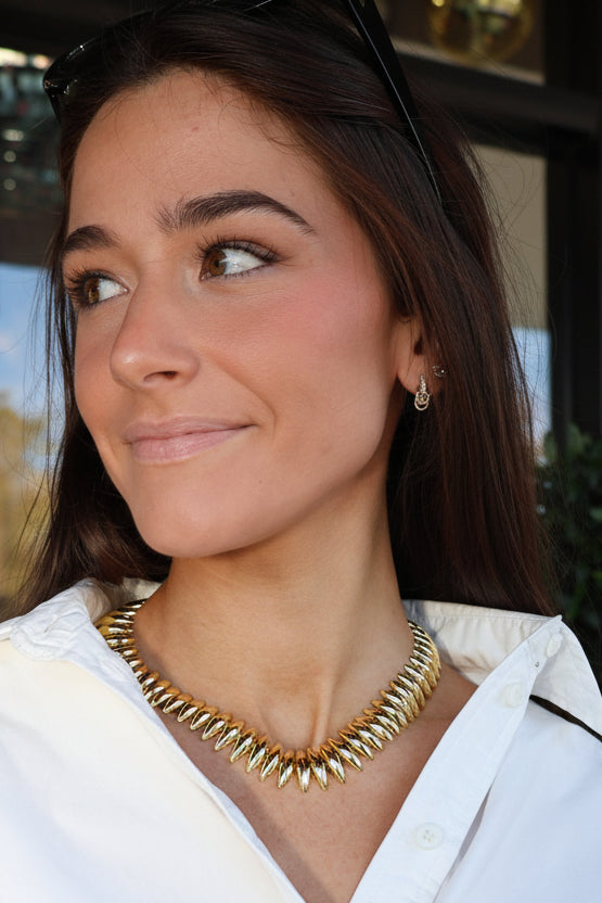 Woman wearing a gold necklace in an outdoor setting
