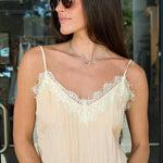 A woman wearing a light beige blush camisole top with white lace trim along the neckline, styled with Highway sunglasses by Z Supply at Rodeo Boutique.