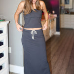 Woman wearing a long dark strapless matching set with white drawstring in a room.