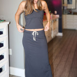 Woman wearing a long dark strapless matching set with white drawstring in a room.