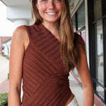 Woman wearing a brown ribbed top standing outdoors.