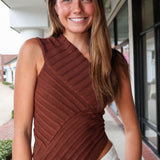 Woman wearing a brown ribbed top standing outdoors.
