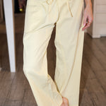 Person wearing light yellow pants on a wooden floor.