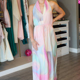 Woman wearing a colorful dress standing in a room with clothing racks and furniture.