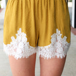 Steve Madden Daisee mustard yellow shorts with lace trim worn by a person.