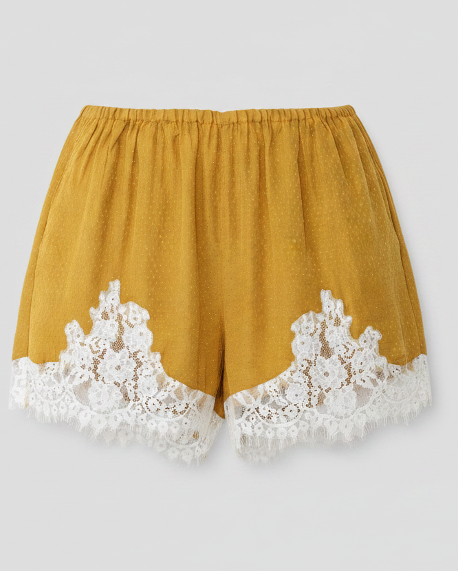 Mustard yellow shorts with white lace trim on a light gray background