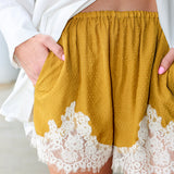 Steve Madden Daisee mustard yellow shorts with lace trim worn by a person.