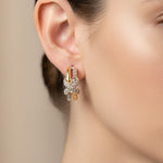 A pair of gold and silver gold butterfly hoop earrings with clear crystals, displayed on a pink 'Rodéo Boutique' card.