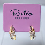A pair of gold and silver gold butterfly hoop earrings with clear crystals, displayed on a pink 'Rodéo Boutique' card.