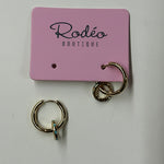 Gold hoop earrings on a pink 'Rodeo Boutique' card against a white background